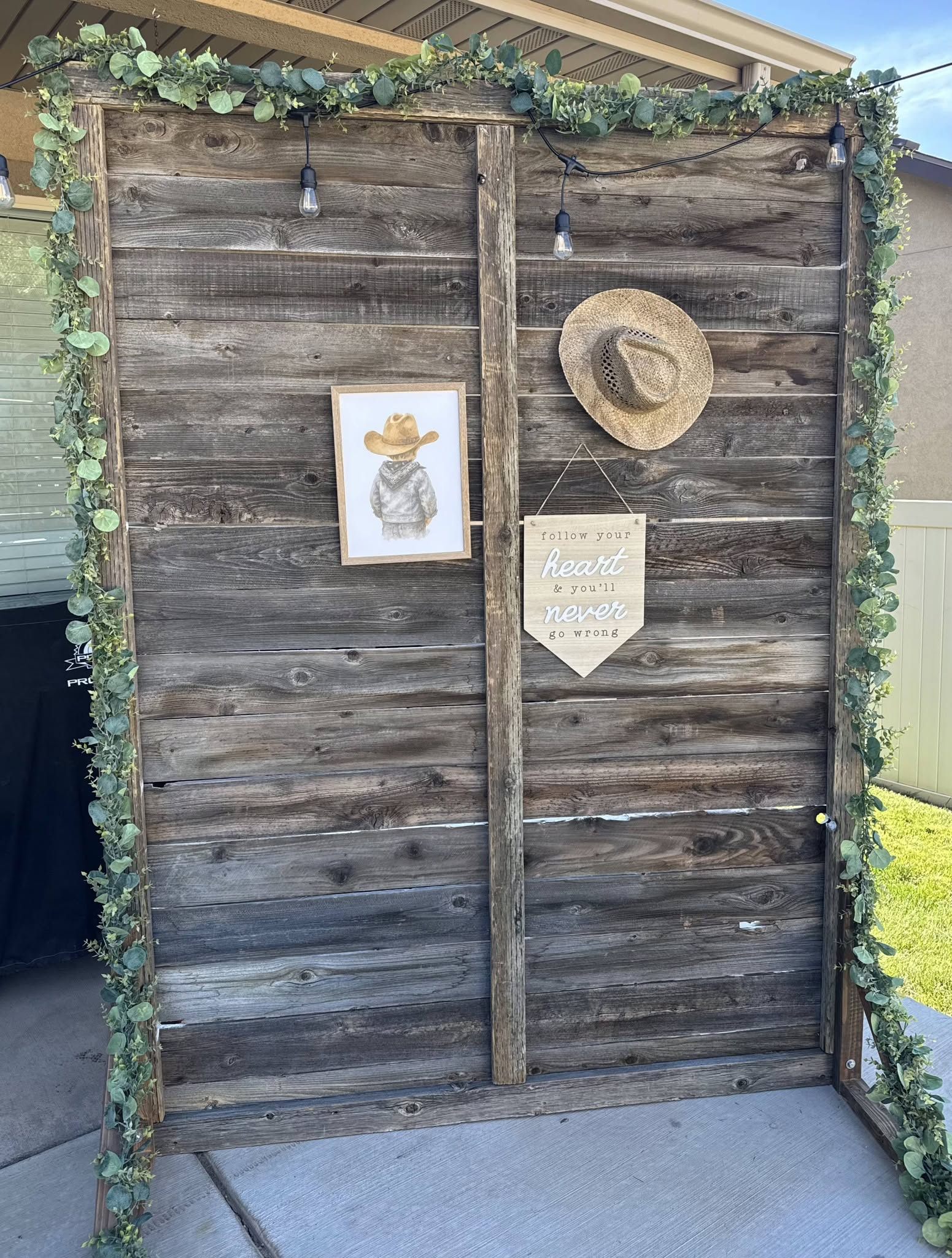 Barnwood backdrop framed with eucalyptus garland and bistro lights