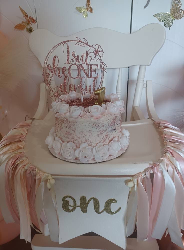First birthday highchair dressed with a ribbon skirt, one banner and a floral smash cake