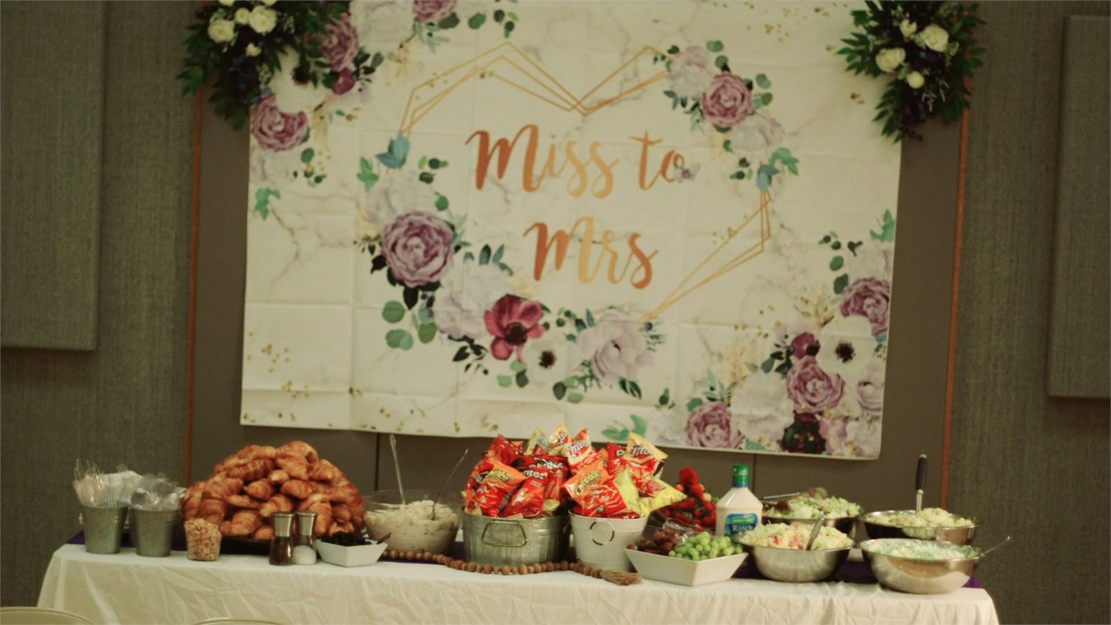 Miss to Mrs bridal shower backdrop with floral corner swags above a food table